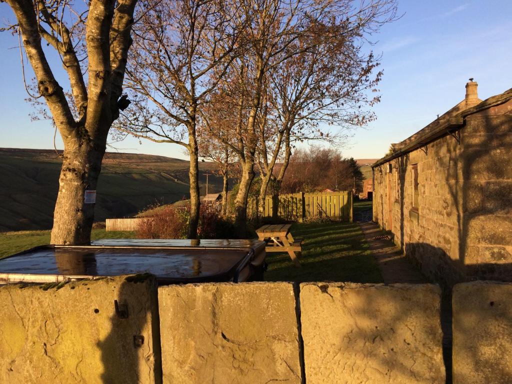 a stone wall with a bench in a yard at Gibraltar Farm Cottage in Hebden Bridge