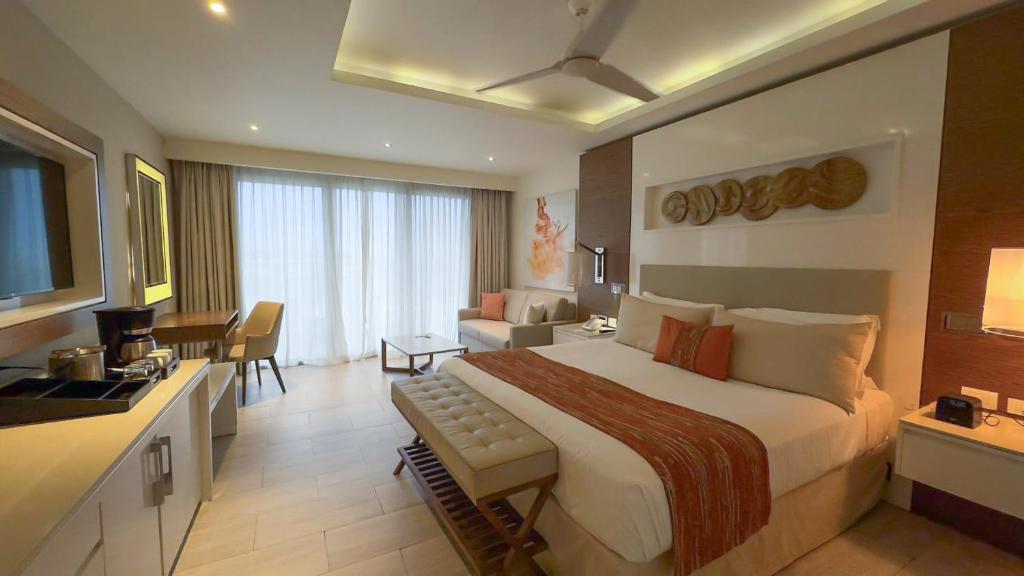 Spacious suite with king bed, separate living area, kitchenette, and ocean view.