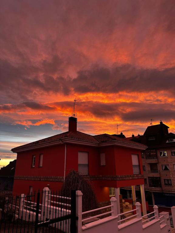 a red house with a sunset in the background at La Calma Candás in Candás