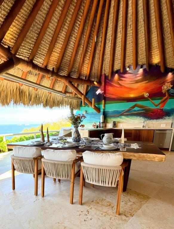 a dining room with a table and chairs and a painting at Oceanfront Designer Penthouse, Private Pool in Ixtapa