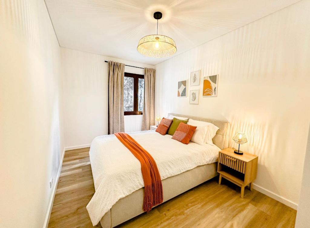 a white bedroom with a bed and a window at Ninho da Ribeira in Ribeira Brava