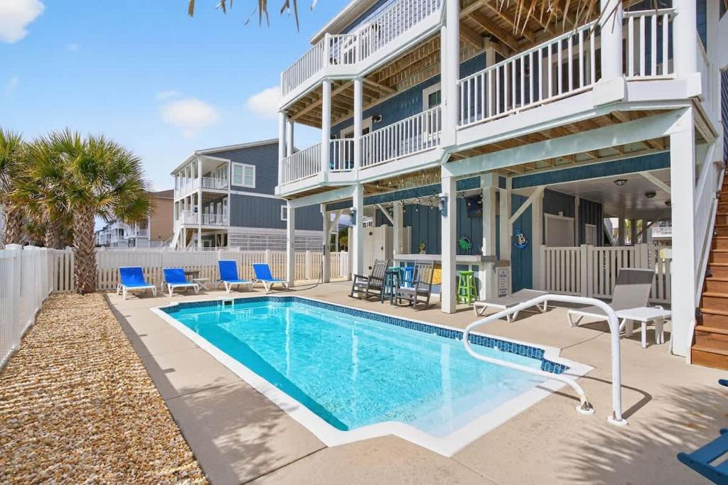 a swimming pool in front of a building with a house at 5 BR Poolside Paradise Just Steps from the Beach in Ocean Isle Beach
