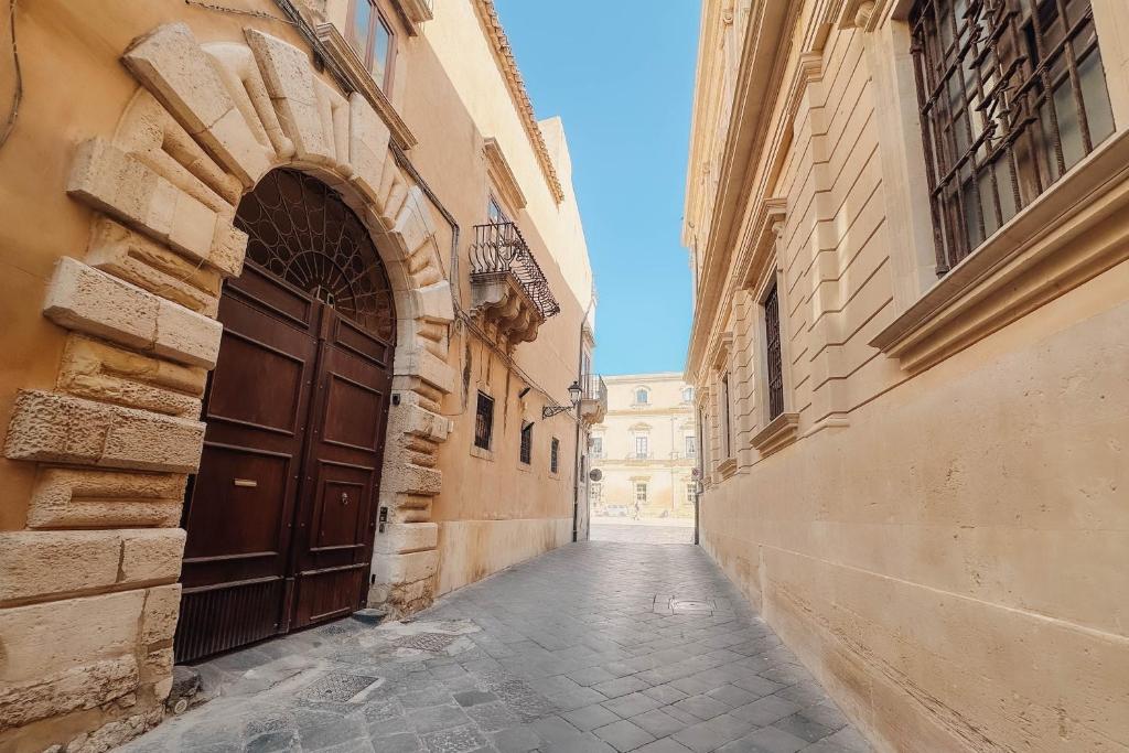 an alley with a large wooden door in a building at CŌRA Ortigia in Syracuse