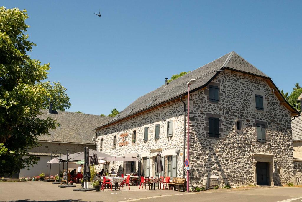 a building with tables and chairs in front of it at Auberge du Cezallier in Montgreleix
