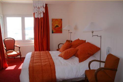 a bedroom with a large bed with orange pillows at Hotel Le Suroit in Perros-Guirec