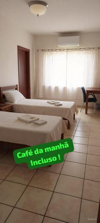 a room with three beds and a sign on the floor at Fazio Hotel in Jales