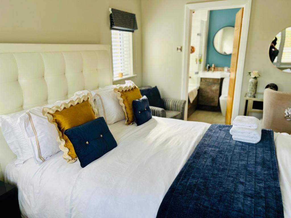 a bedroom with a large white bed with yellow and blue pillows at Wendys house in Sarisbury Green