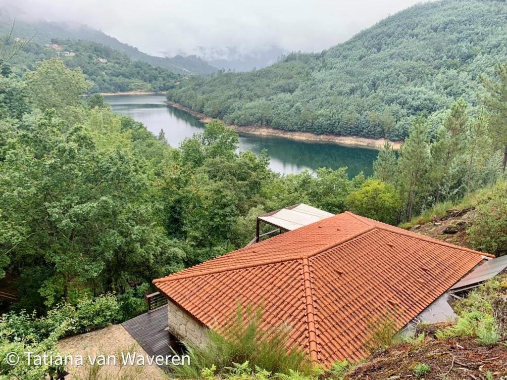 an orange roofed house on a hill next to a river at Sorte do Jugo - Lakeside cottage with private beach in Vieira do Minho
