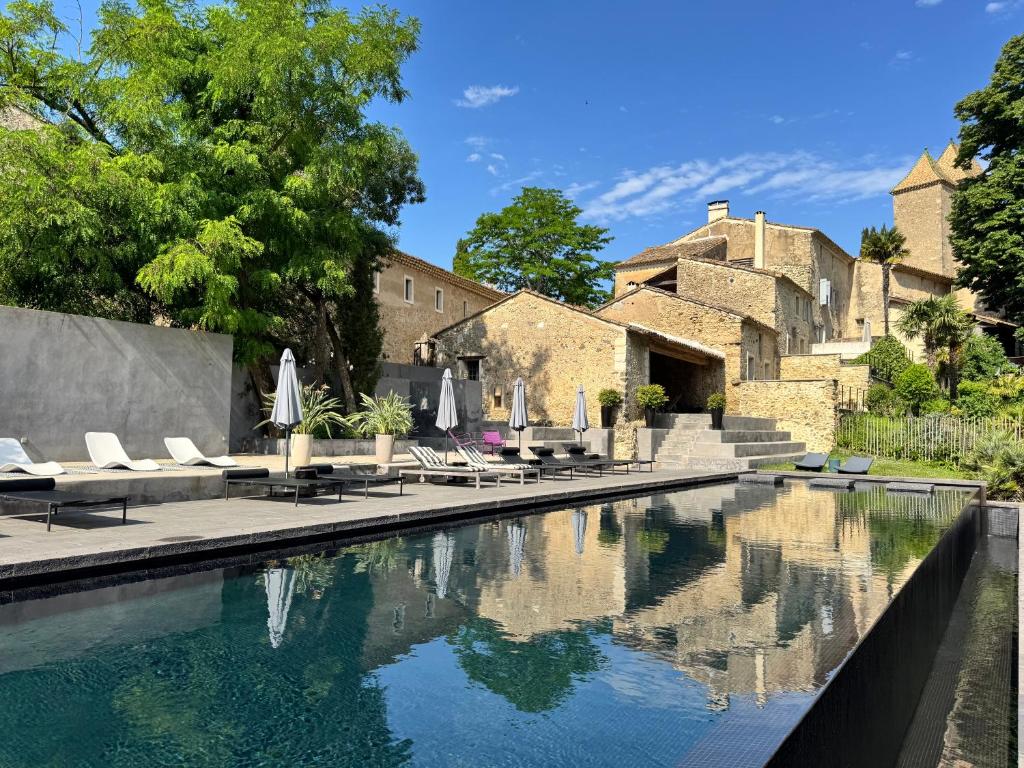 a pool with chairs and umbrellas in front of a building at Domaine de Ribaute in Lieuran-lès-Béziers