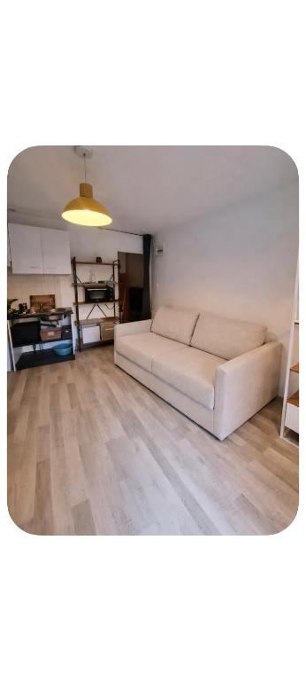 a living room with a white couch and wooden floors at Studio pour 2 en plein centre-ville in Dol-de-Bretagne