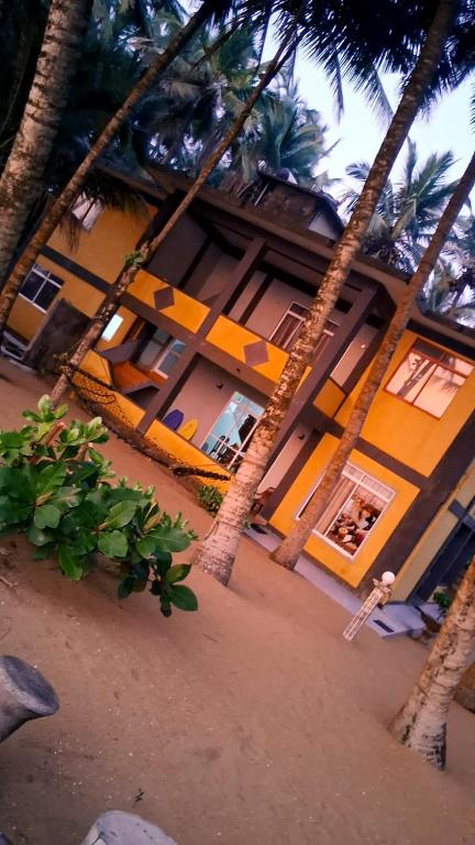 a person standing in front of a building with palm trees at Jasmin Garden in Kalutara