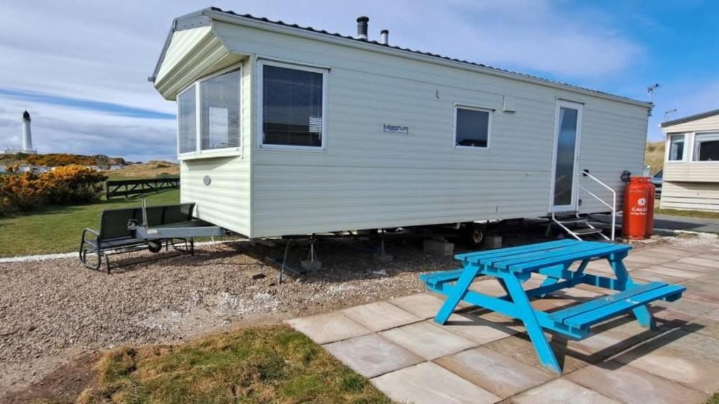 a tiny house with a picnic table and a bench at Aurora on the Dunes- Cozy Coastal Retreat with Scenic Views in Lossiemouth