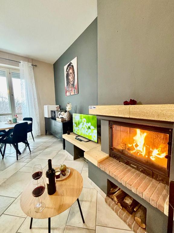 a living room with a fireplace and a table with wine glasses at Suite Altura in Cuneo