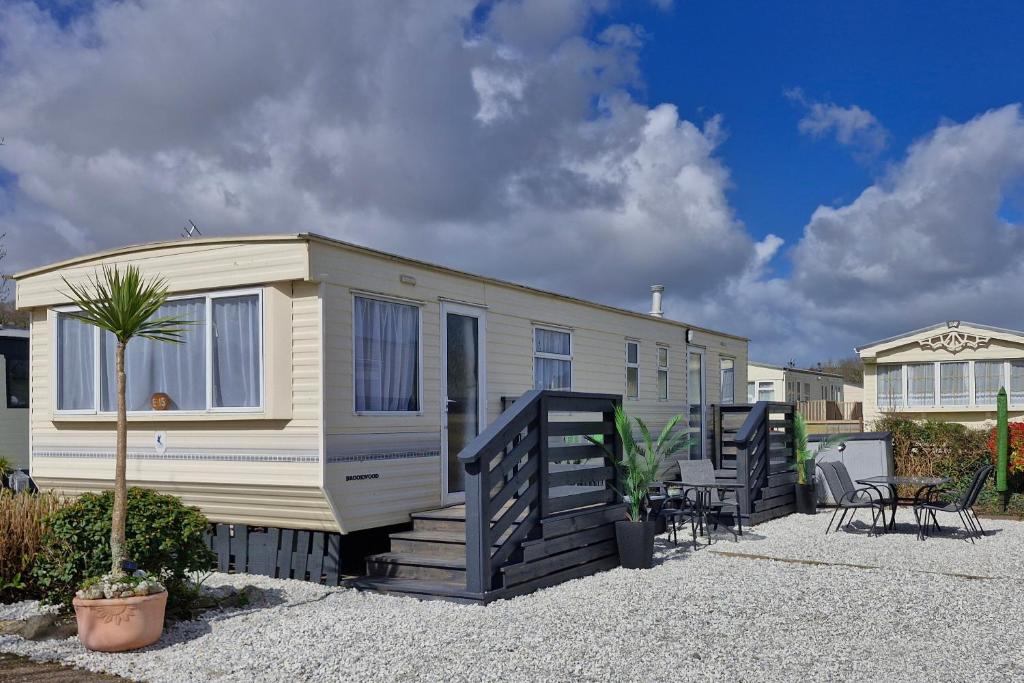 a small white caravan with a porch and a patio at Palm Court - 3 Bed Heated Pool Parking Nr Beach in Par