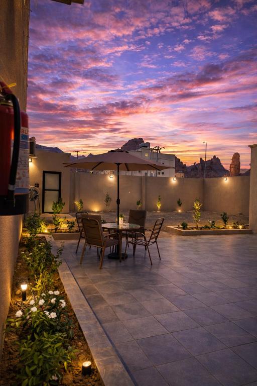 a patio with a table and chairs and an umbrella at نسيم العلا - Naseem AlUla in Al-ʿUla