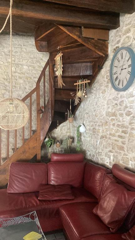 a living room with a red couch and a clock at Le Caillou in Reuilly