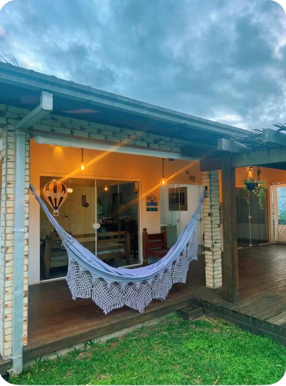 a hammock on the porch of a house at Casa completa com lareira, piscina compartilhada in Torres