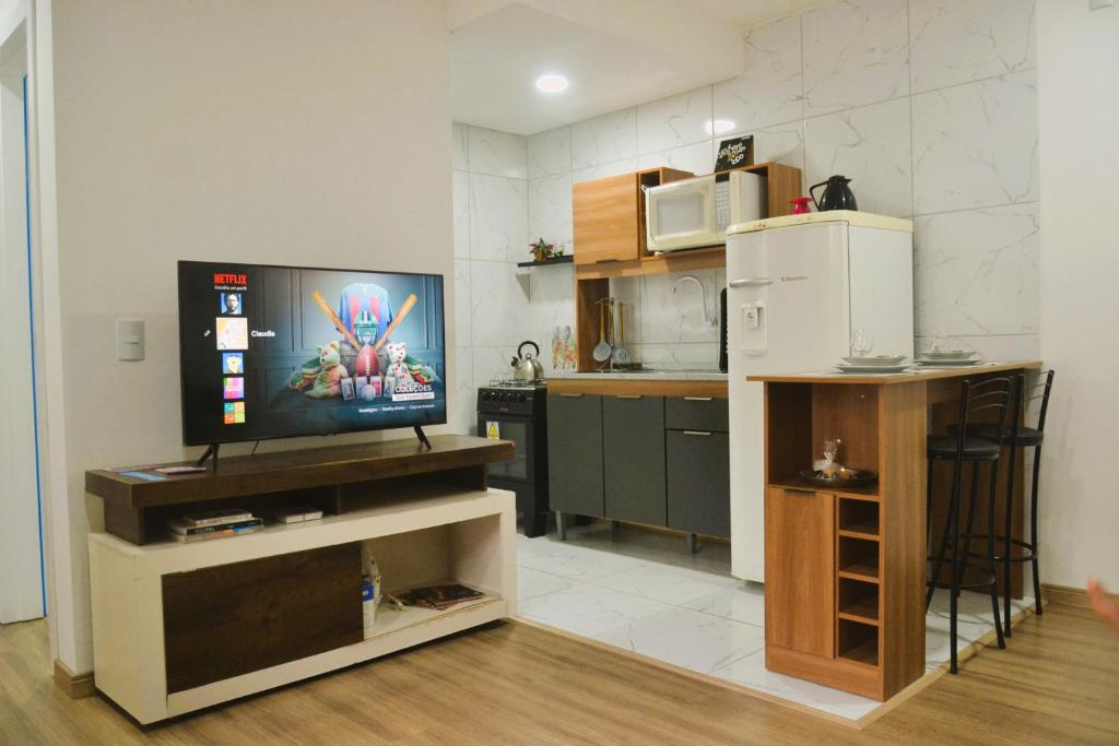 a living room with a television and a kitchen at Refúgio completo com Ar condicionado e enxoval in Pelotas