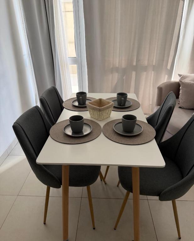 a white table with black chairs and cups on it at Brisa del mar in Comodoro Rivadavia