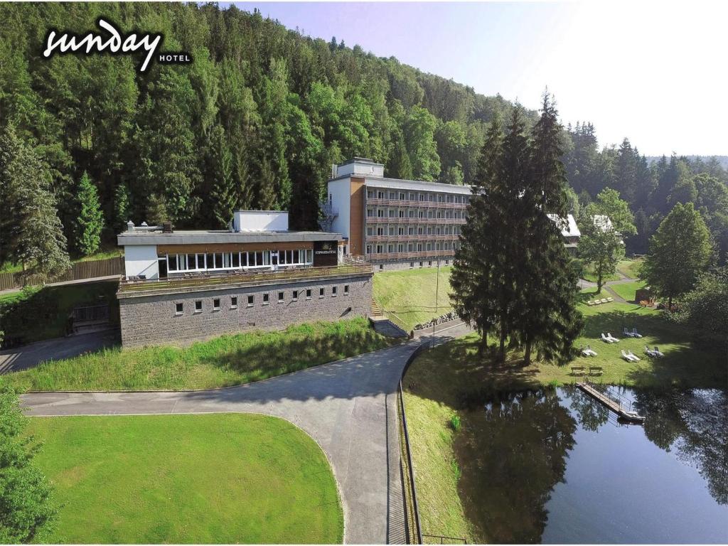 a building next to a body of water with trees at Sunday Schwarzbachtal Double Room Forest View in Erlbach