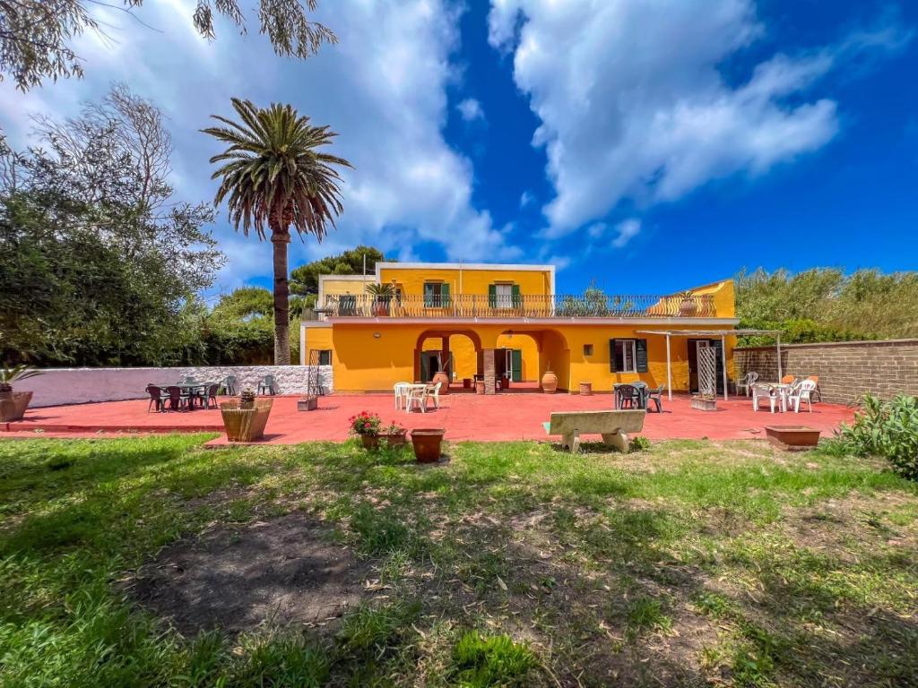 a yellow house with tables and chairs in a yard at Antico Casale Ventotene in Ventotene