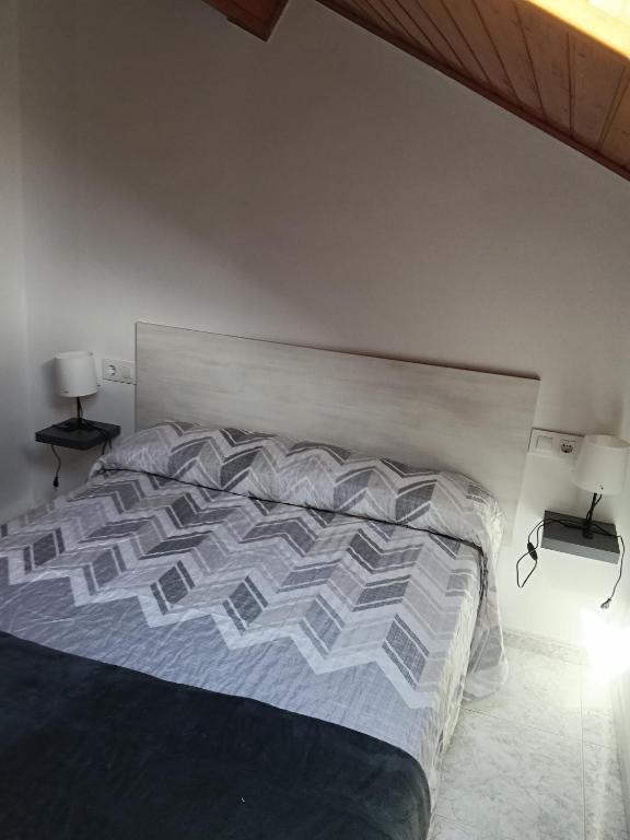 a bed in a bedroom with two lamps and two tables at Rías Baixas in Villanueva de Arosa