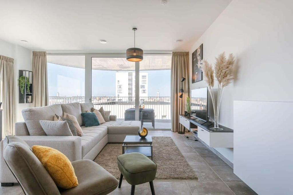 a living room with a couch and a tv at Casiola - Bright apartment with seaview in Bredene