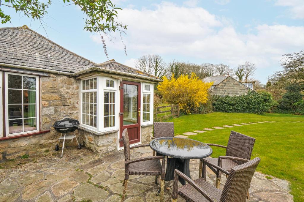a patio with chairs and a table and a grill at Tumrose Cottage in Blisland