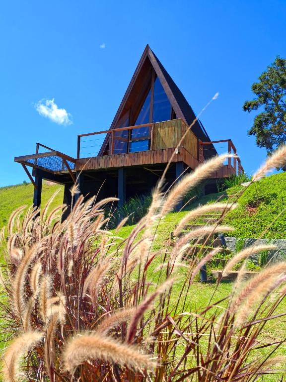 a house on top of a hill with grass at Cabana Quatro Estações - Luxo Romântica e com vista incrível in Paty do Alferes