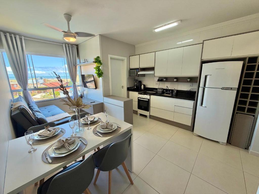 a kitchen with a white table and chairs and a refrigerator at Apartamento com vista mar e perto da praia in Tramandaí