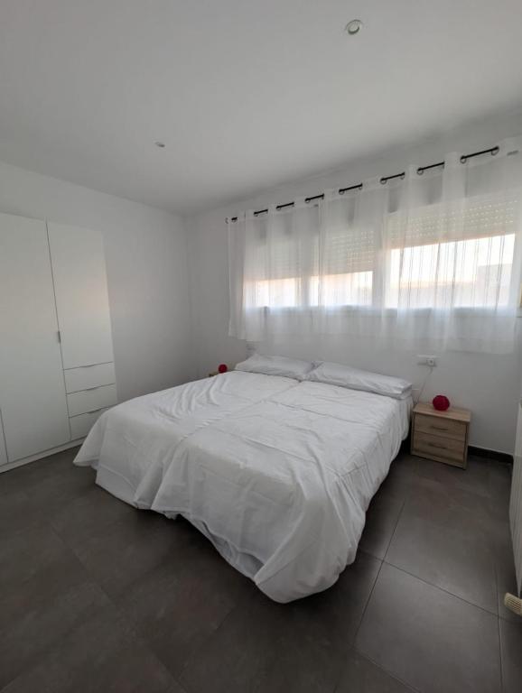 a white bedroom with a white bed and a window at Casa Diego in Alcañiz