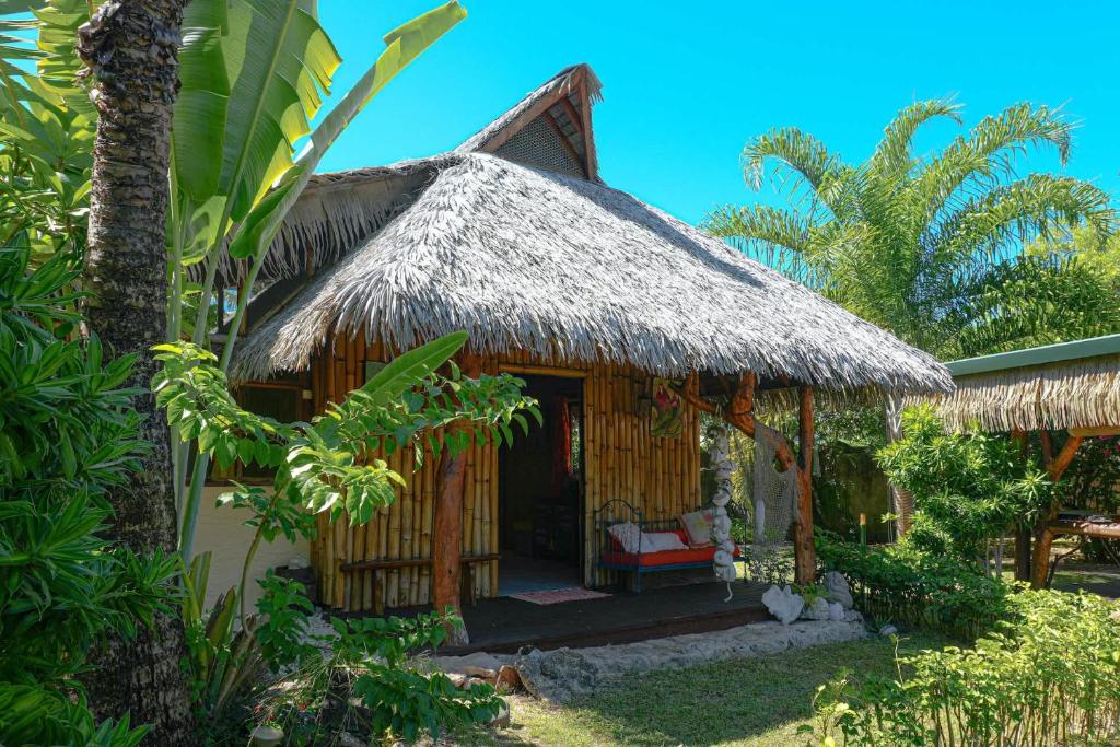 a small hut with a thatch roof and a chair at Charming 1BR Garden Bungalow in Temae