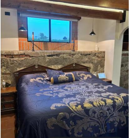 a bedroom with a bed with a blue comforter at Hotel Boutique Santa Teresa in Tlazcalancingo