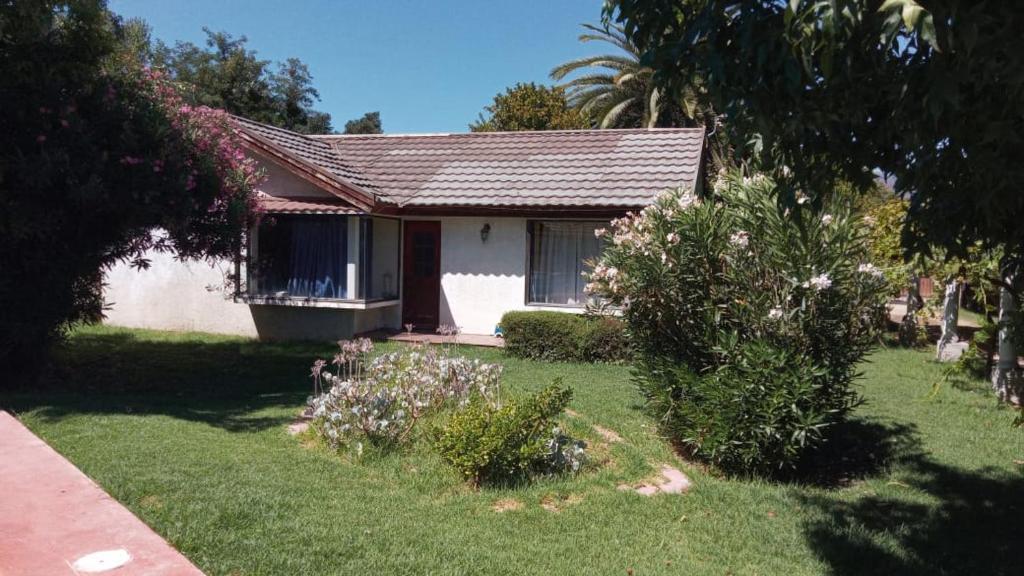 a small white house with a yard with flowers at Chalet yuris in Melipilla