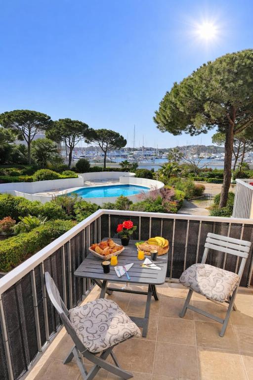 a table and chairs on a balcony with a pool at Studio cosy, Centre Port, Piscine, proche plage in Cap d'Agde