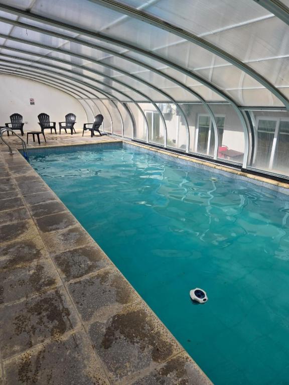 an indoor swimming pool with blue water in a building at Casa del Parque estudio 4 pax in Necochea