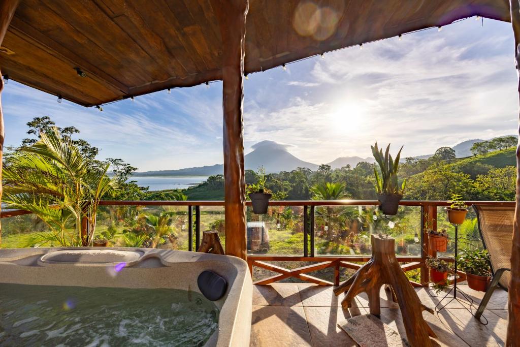 a hot tub on a deck with a view of the ocean at Lua Pele House - Arenal Volcano & Lake views in El Castillo de La Fortuna