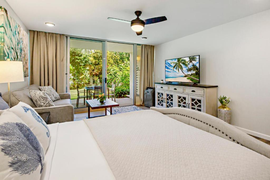 a bedroom with a white bed and a television at Napili Puamala 128 in Kahana