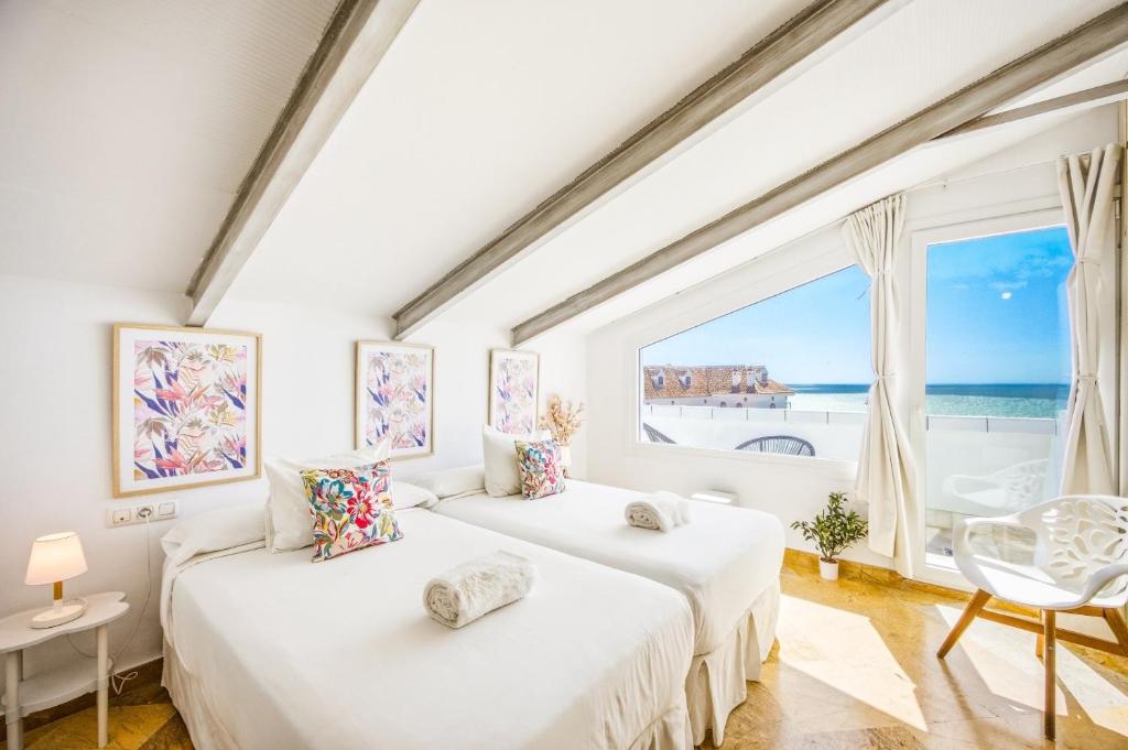 two beds in a room with a large window at Labreña Hotel in Los Caños de Meca