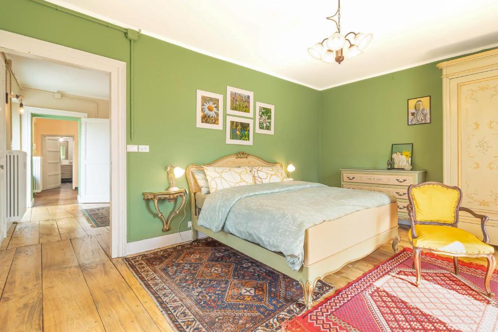 a bedroom with green walls and a bed and a chair at La Quiete del Mattino in Torre Pellice
