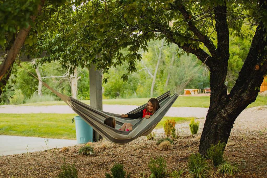 a girl sitting in a hammock under a tree at The Blue Jay at Zen Zion in Glendale