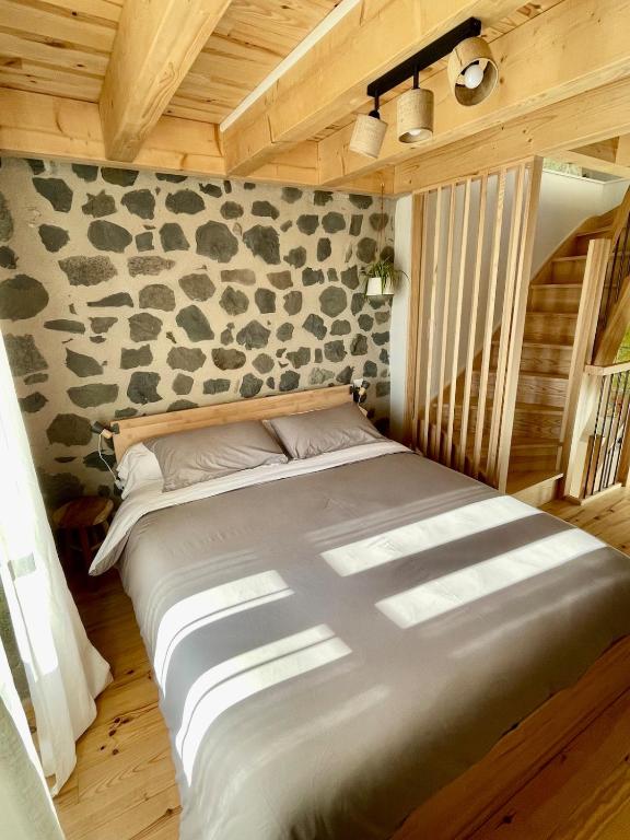 a bed in a room with a stone wall at Abri Tiny House in Murat