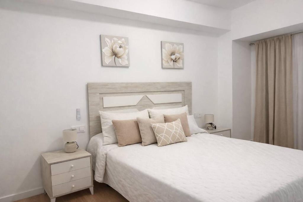 a bedroom with a white bed with two pictures on the wall at Alojamiento Baeza - Leones 9 A in Baeza