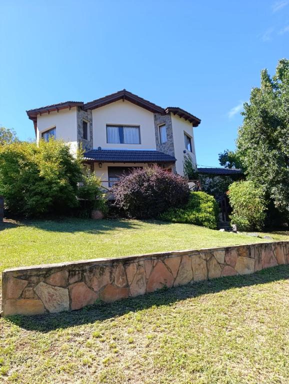 a house with a stone wall in front of a yard at Casas Altas VGB in Villa General Belgrano