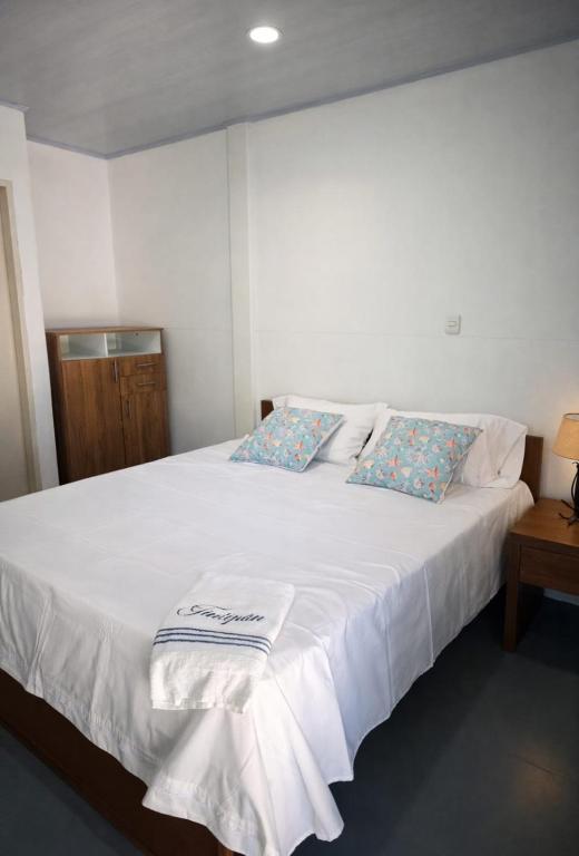 a white bed with two pillows on top of it at Aquitania in Rincón