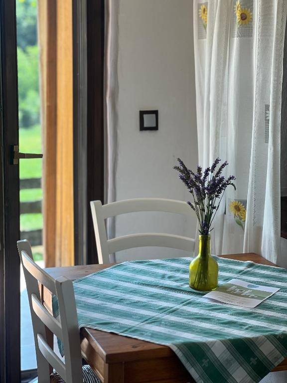 a table with a green vase with flowers on it at Apartments Mali Raj in Dolenci