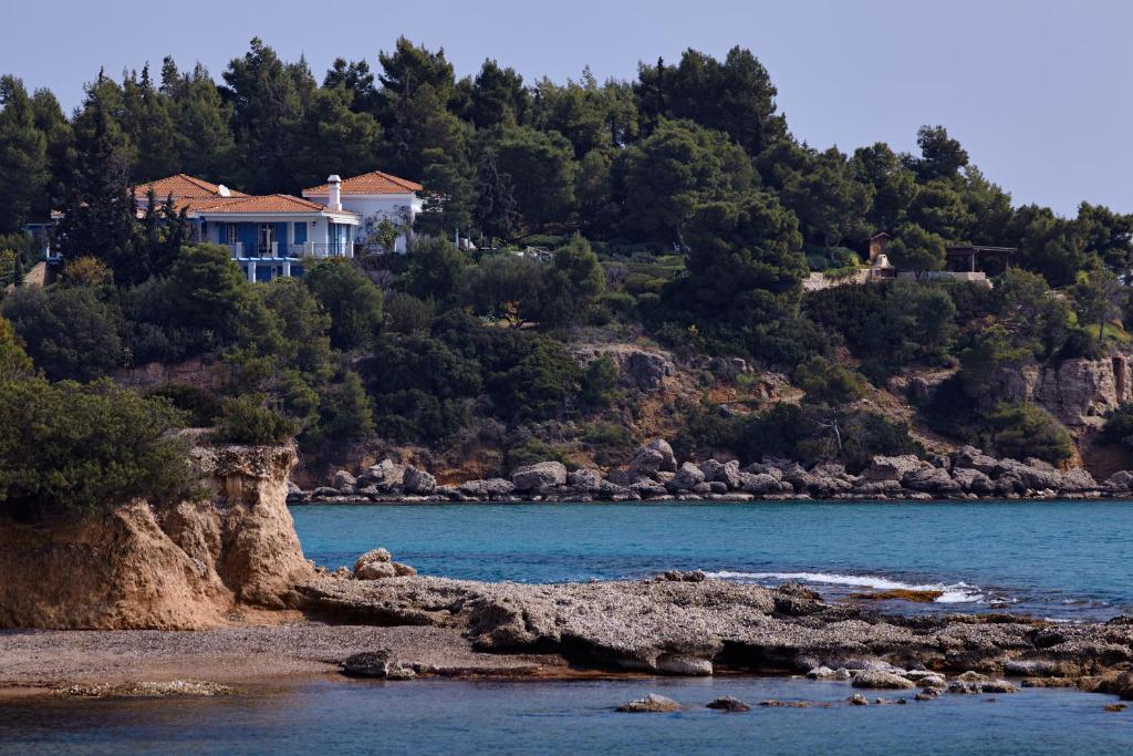 ein Haus auf einem Hügel neben einem Wasserkörper in der Unterkunft Villa Irini in Porto Heli