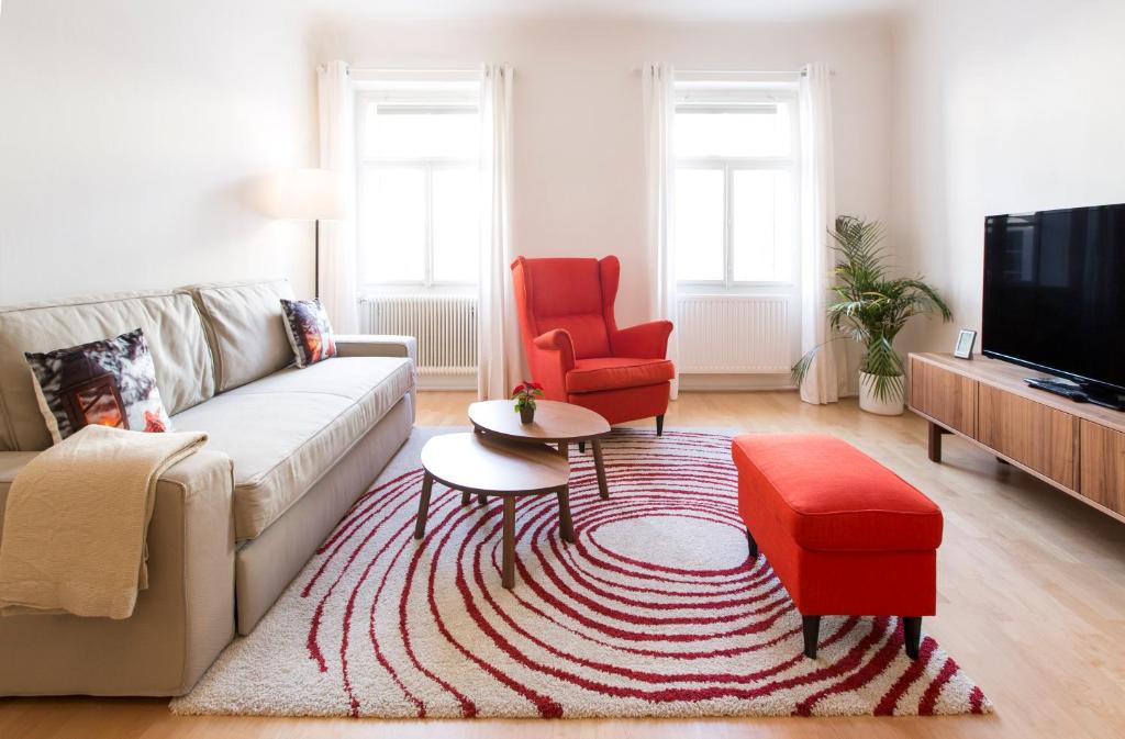 ザルツブルクにあるNext2Mozart-Apartmentのリビングルーム(白いソファ、赤い椅子付)