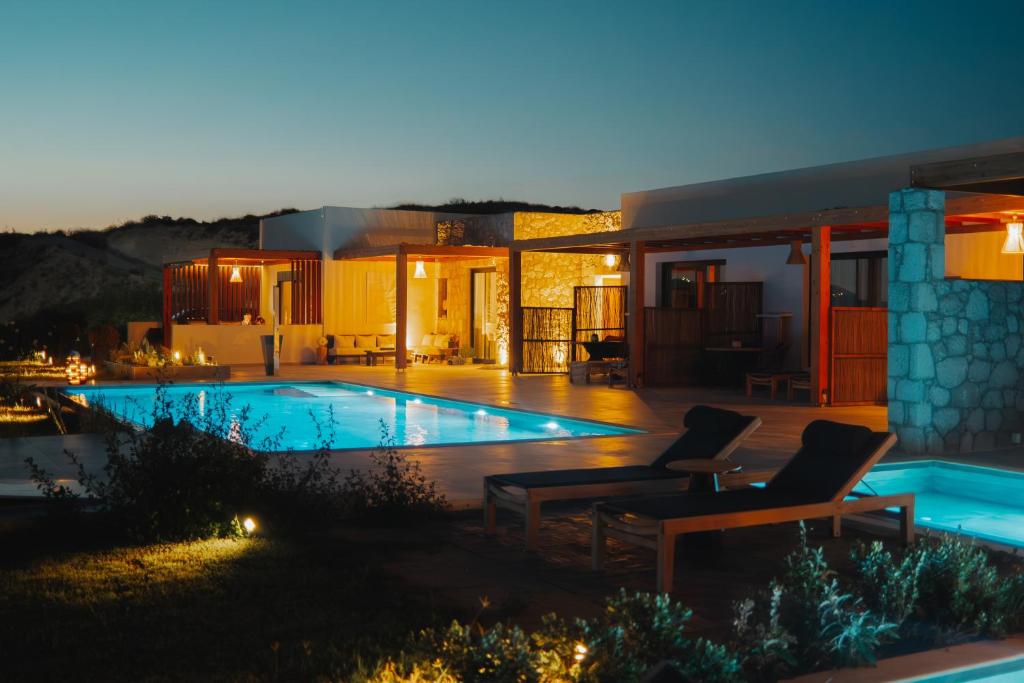 a villa with a swimming pool at night at Obsidian Suites Milos in Mytakas