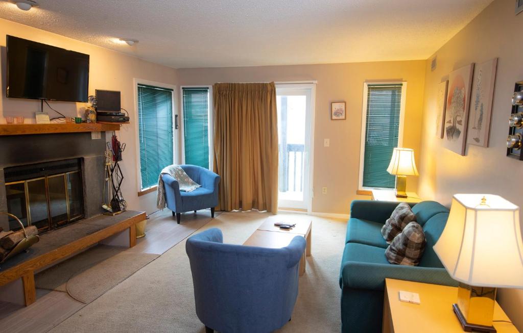 a living room with blue furniture and a fireplace at Mountain Lodge at Okemo, A Vail Resorts Property in Ludlow